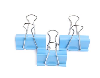 Photo of Blue binder clips on white background, top view. Stationery item