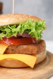 Delicious burger with tofu and fresh vegetables on wooden board, closeup