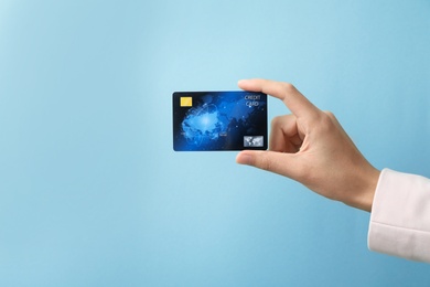 Woman holding credit card on color background