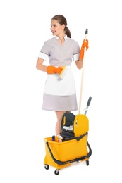 Young chambermaid with cleaning supplies on white background