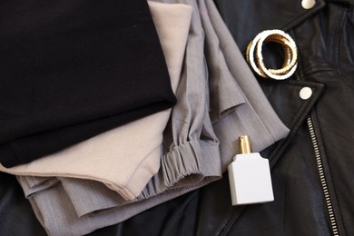 Folded clothes, bracelets, bottle of perfume and black leather jacket , flat lay