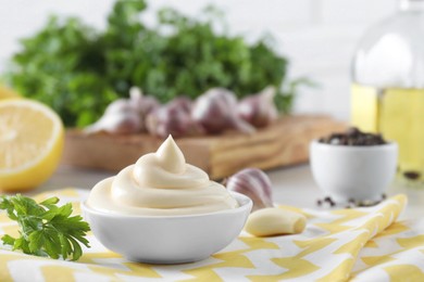 Photo of Tasty mayonnaise sauce in bowl and parsley on table, closeup. Space for text