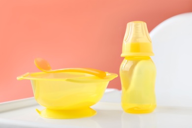 Photo of Set of plastic dishware on white feeding table. Serving baby food