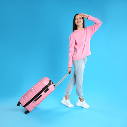 Photo of Beautiful woman with suitcase for summer trip on blue background. Vacation travel