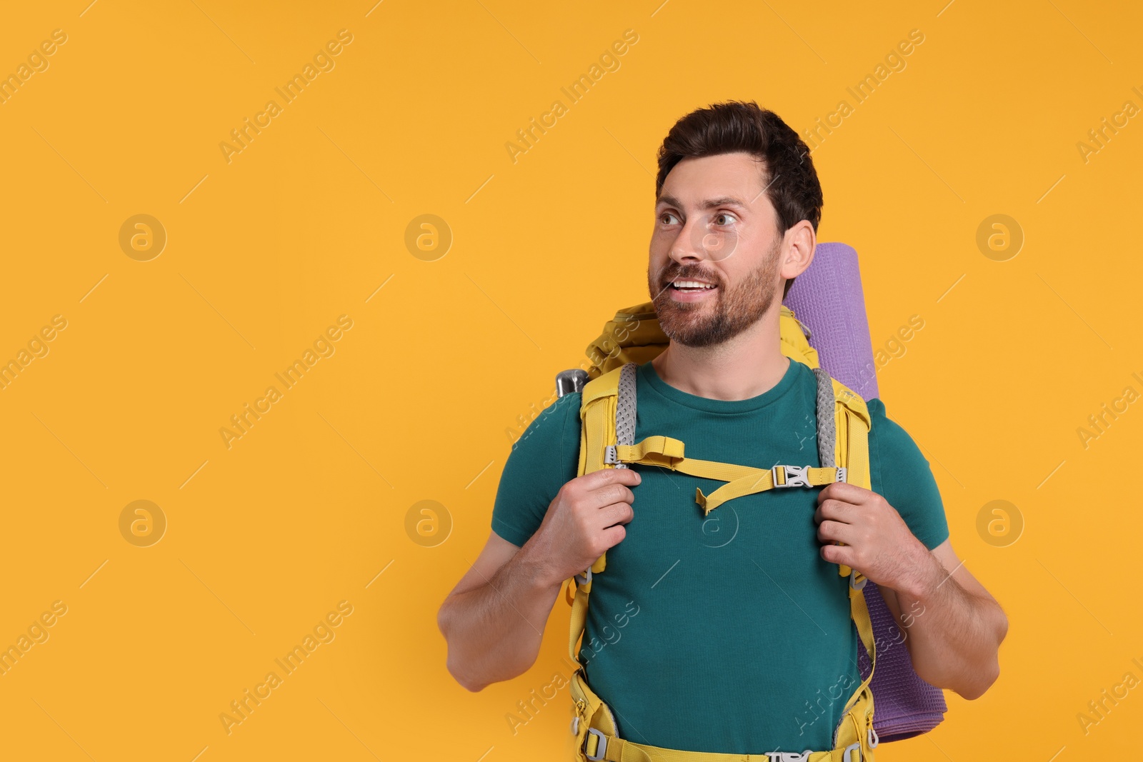 Photo of Happy man with backpack on orange background, space for text. Active tourism