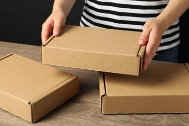 Photo of Packaging goods. Woman with cardboard boxes at wooden table, closeup