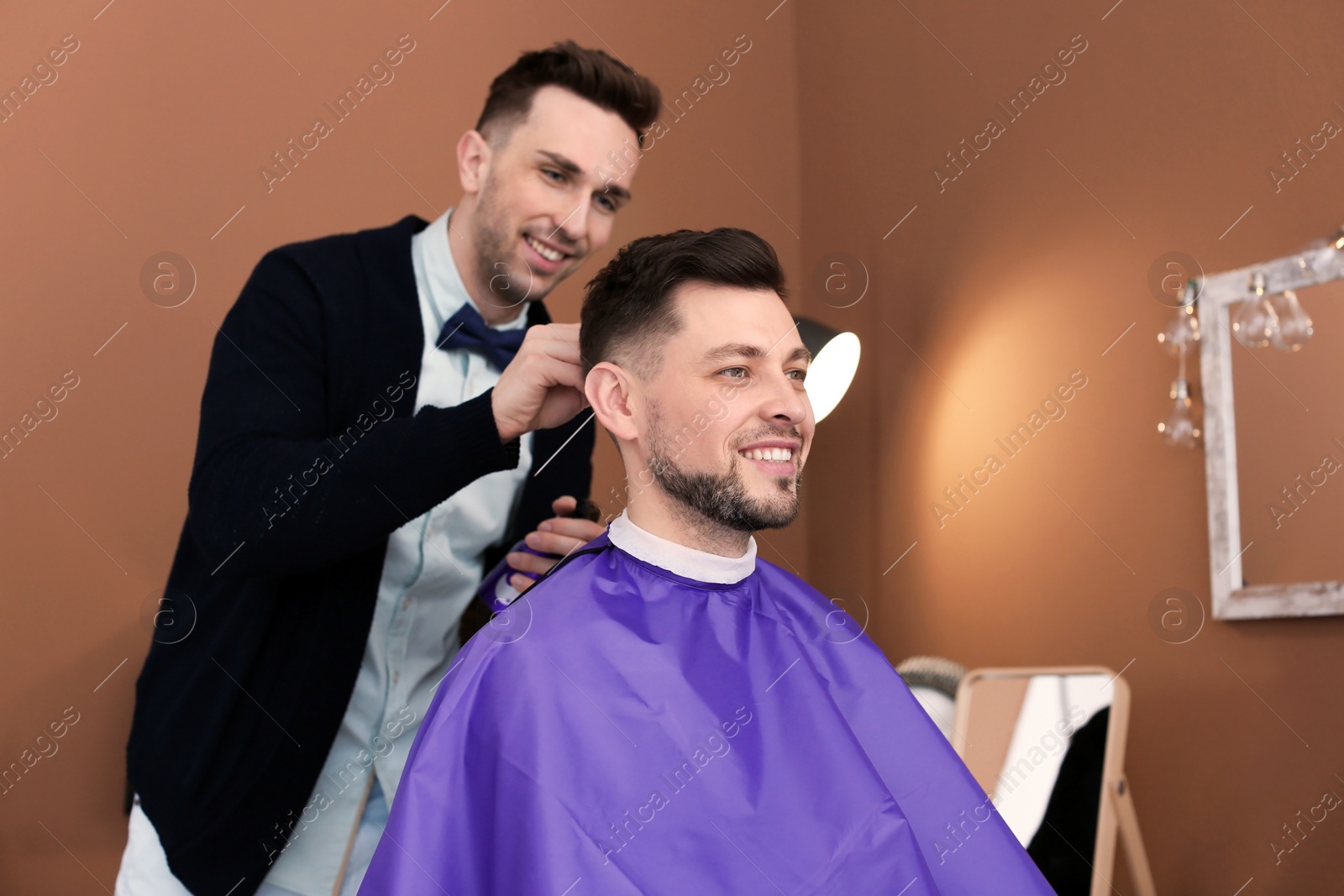 Photo of Professional hairdresser working with client in beauty salon