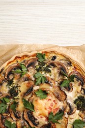 Photo of Delicious quiche with mushrooms and parsley on white wooden table, top view. Space for text