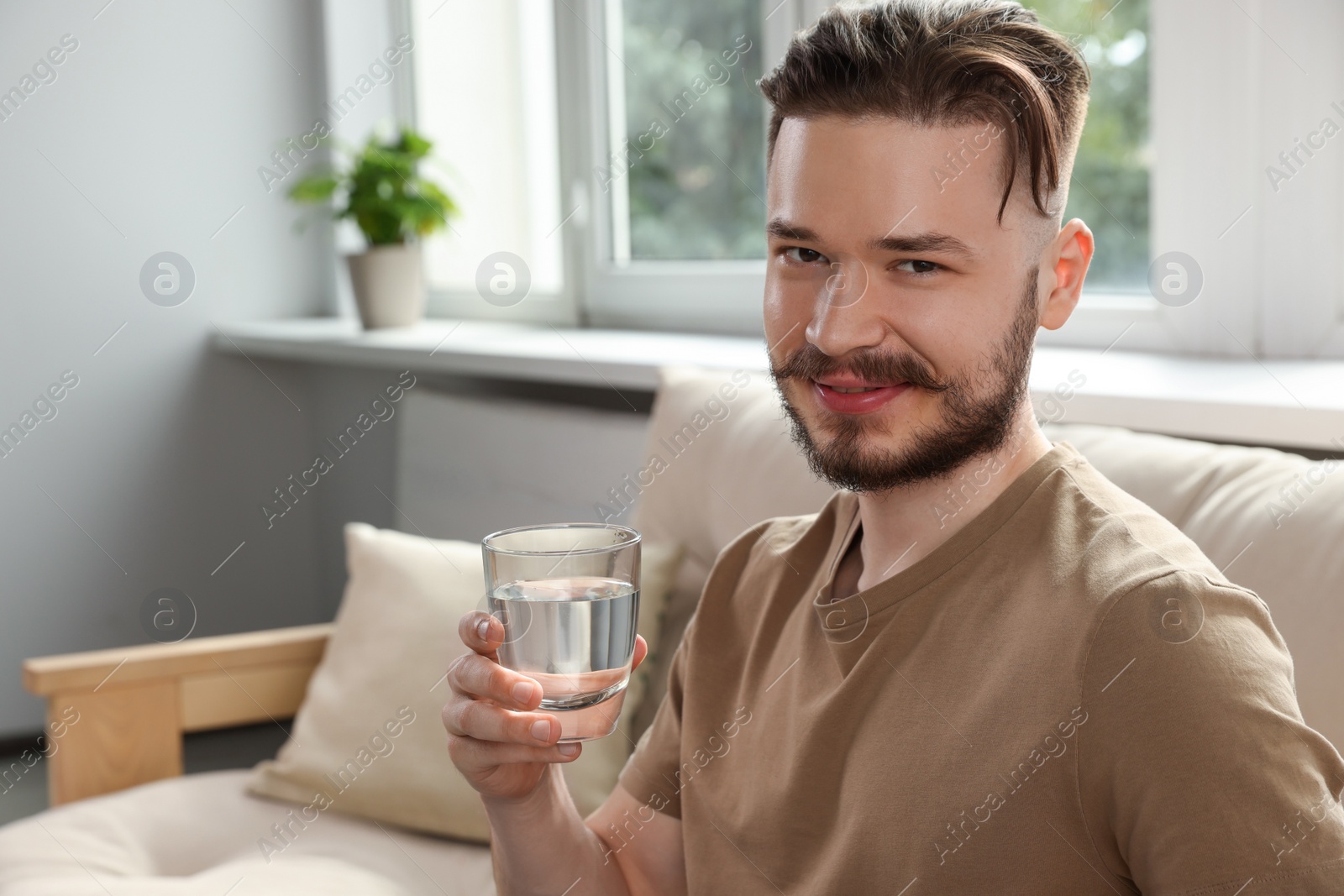 Photo of Handsome man with glass of water at home. Refreshing drink
