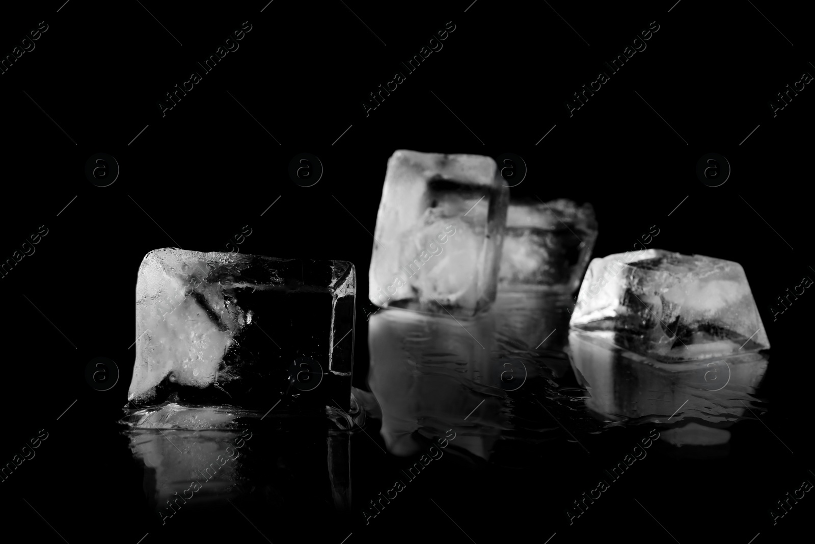 Photo of Transparent ice cubes on black mirror surface