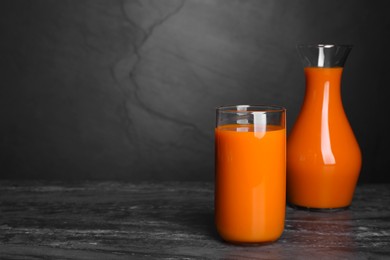 Tasty carrot juice on black marble table, space for text