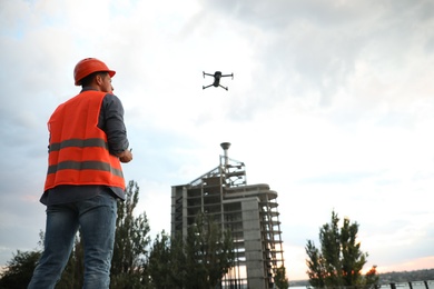 Builder operating drone with remote control at construction site. Aerial survey