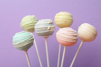 Photo of Sweet colorful cake pops on purple background