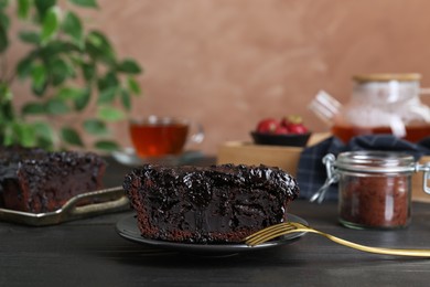 Piece of tasty chocolate sponge cake on black wooden table