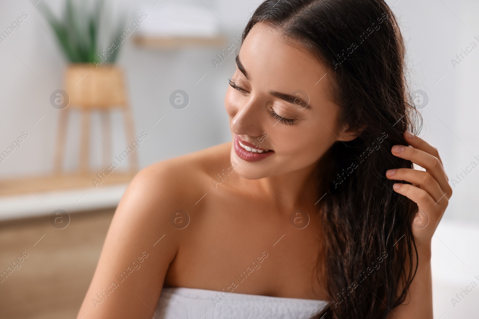 Photo of Young woman applying aloe hair mask in bathroom