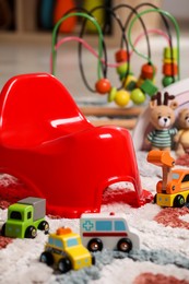 Photo of Red baby potty and toys on carpet in room. Toilet training