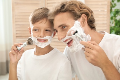 Photo of Father and son shaving together in bathroom