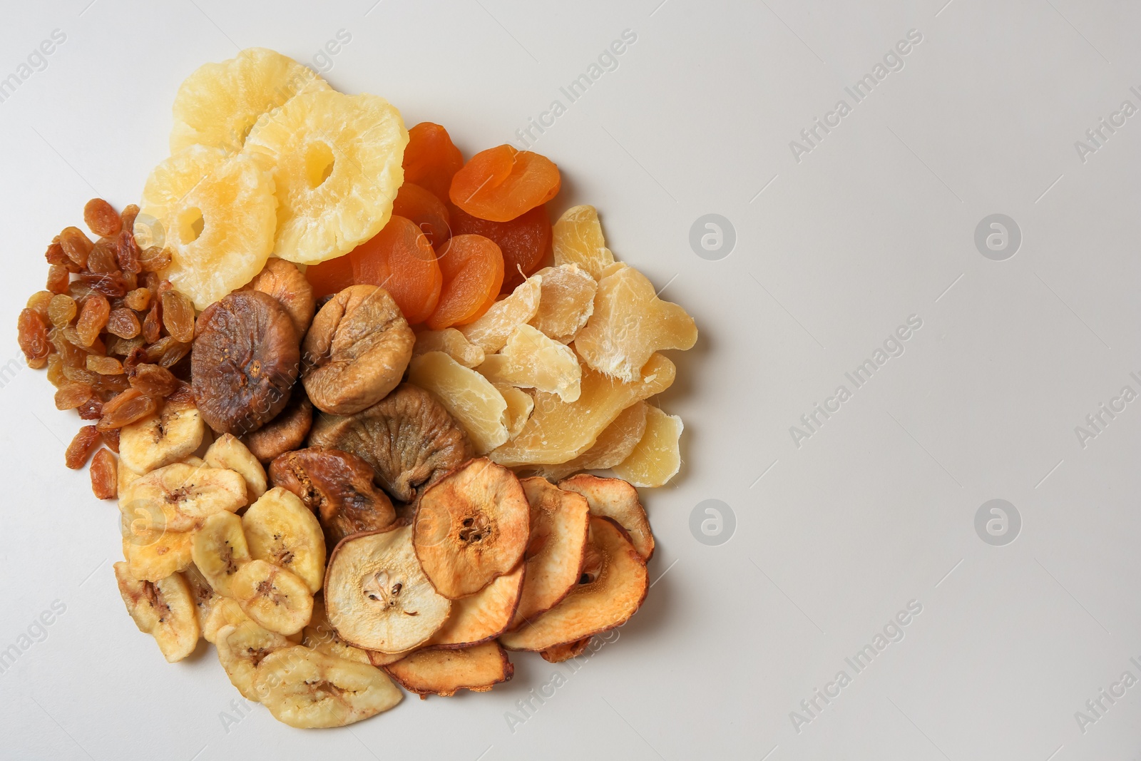 Photo of Pile of different dried fruits on white background, top view. Space for text