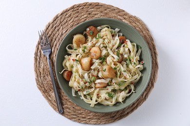 Delicious scallop pasta with spices in bowl served on white table, flat lay