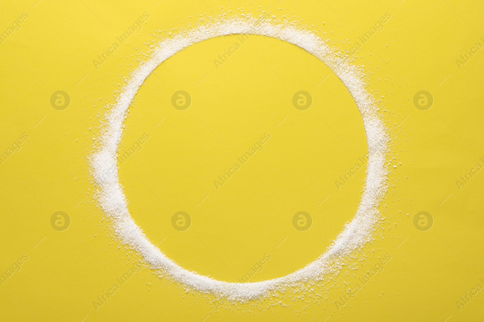 Photo of Frame made of granulated sugar on yellow background, top view. Space for text