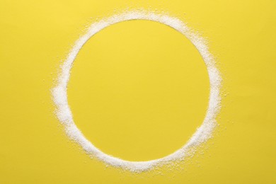 Photo of Frame made of granulated sugar on yellow background, top view. Space for text