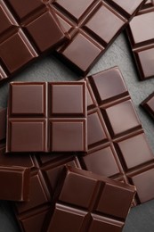 Photo of Delicious dark chocolate on black table, flat lay