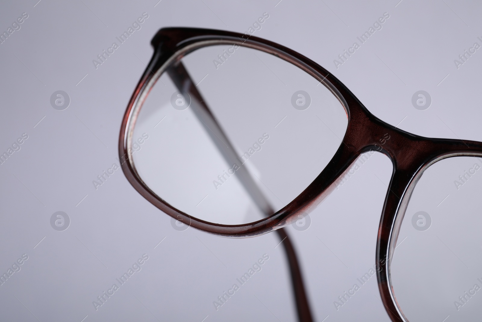 Photo of Stylish pair of glasses with brown frame on light grey background, closeup