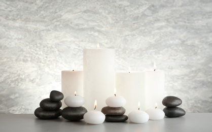 Photo of Beautiful composition with candles and stones on table against light background