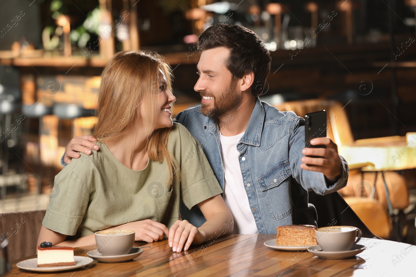 Photo of Romantic date. Happy couple taking selfie in cafe