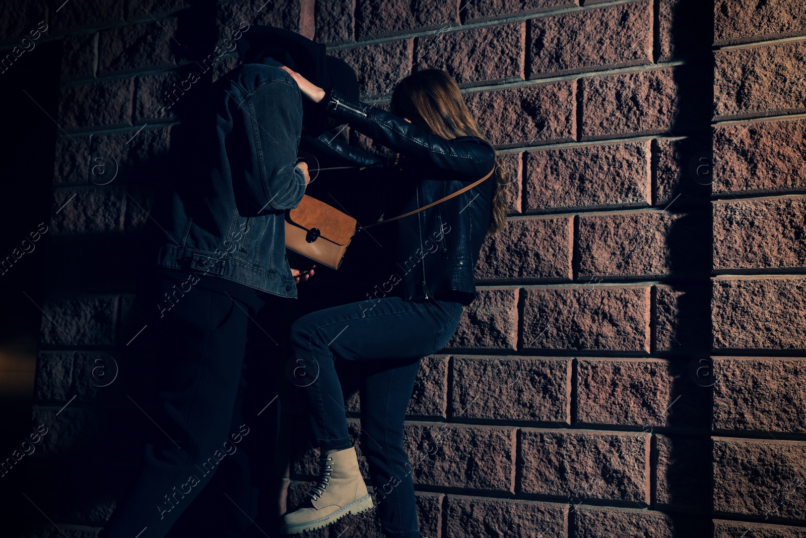 Photo of Woman fighting with thief while he trying to steal her bag outdoors at night. Self defense concept