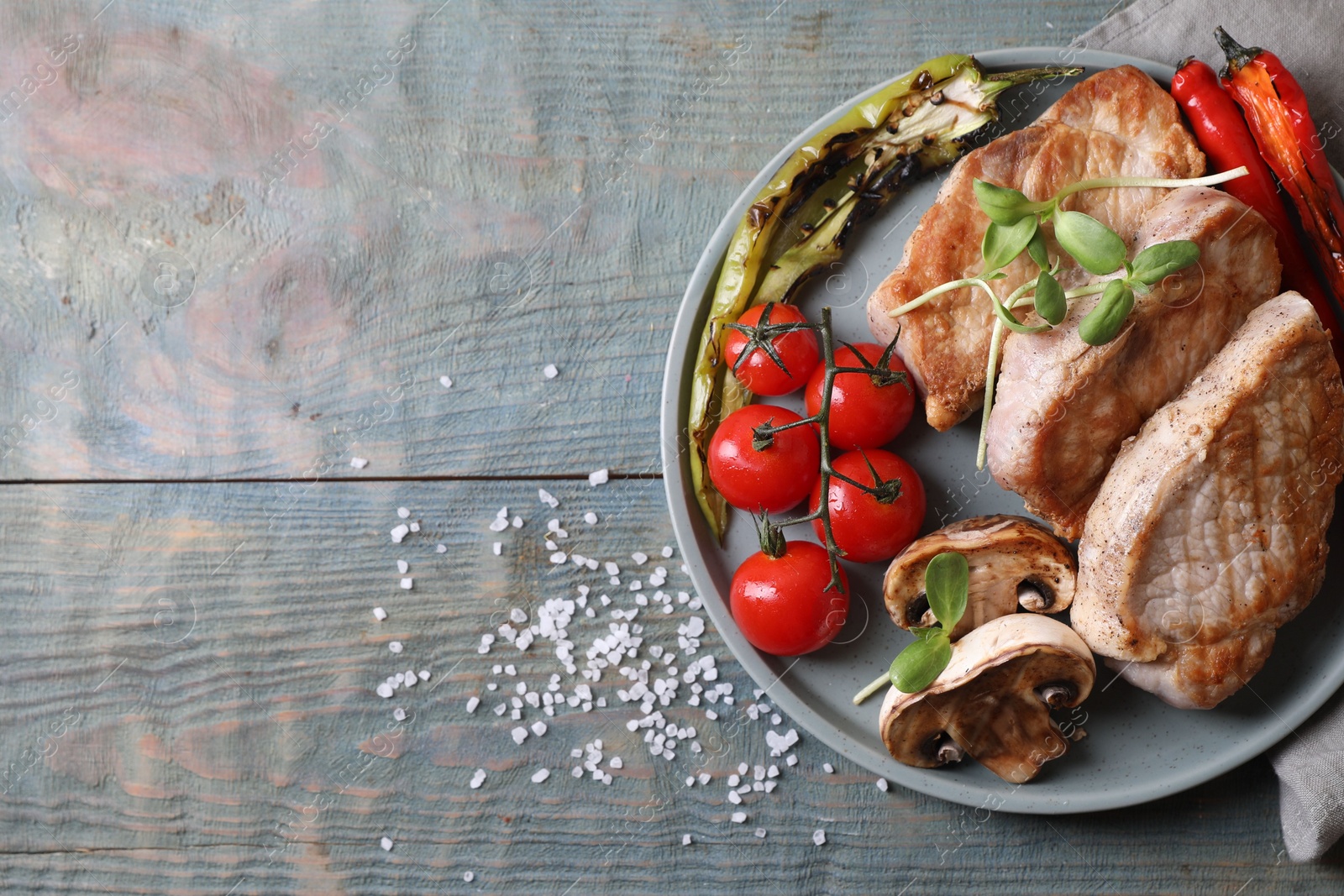 Photo of Delicious grilled meat and vegetables served on wooden table, flat lay. Space for text