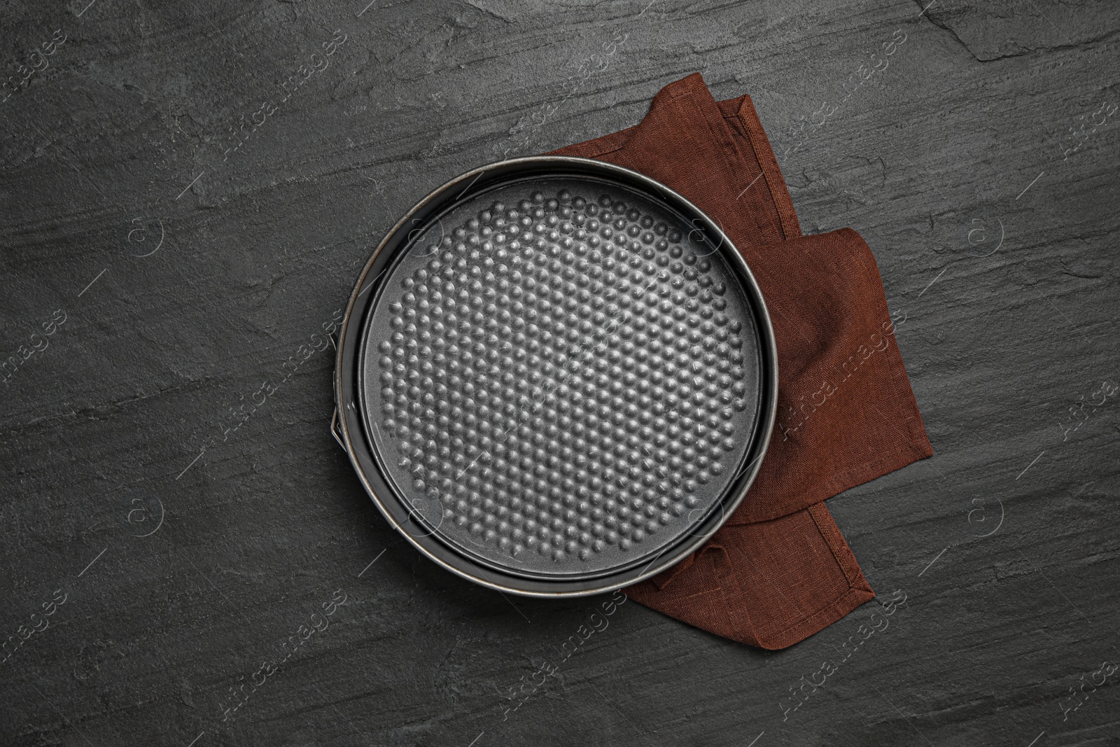 Photo of Baking dish and brown cloth on black table, flat lay. Cooking utensil