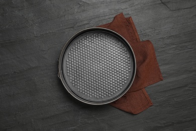 Photo of Baking dish and brown cloth on black table, flat lay. Cooking utensil