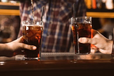 Couple with glasses of refreshing cola at bar counter, closeup