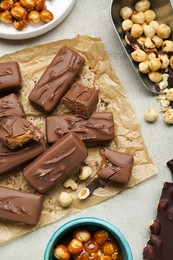 Photo of Delicious chocolate candy bars and nuts on light table, flat lay