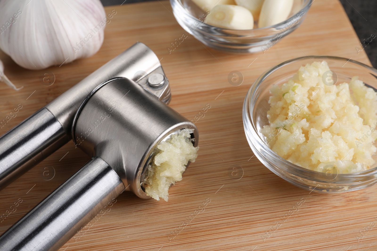 Photo of Garlic press and mince on wooden table, closeup