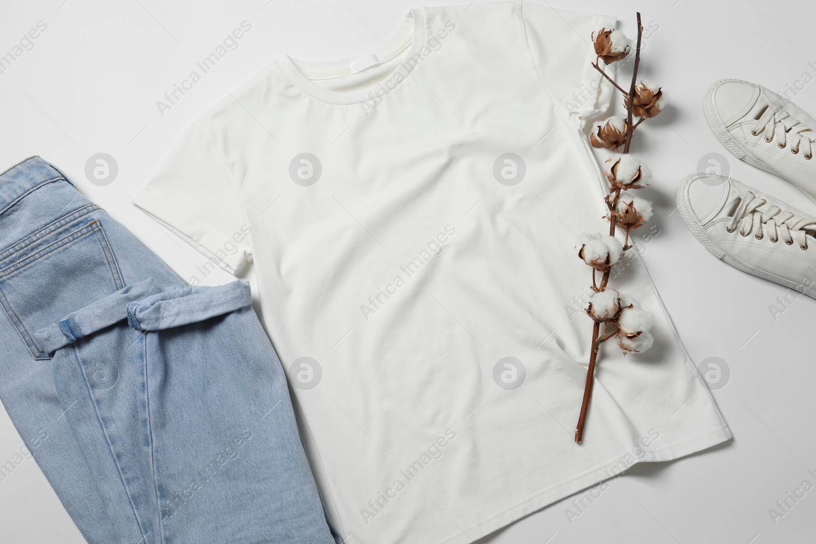 Photo of Stylish t-shirt, jeans and sneakers on white background, flat lay