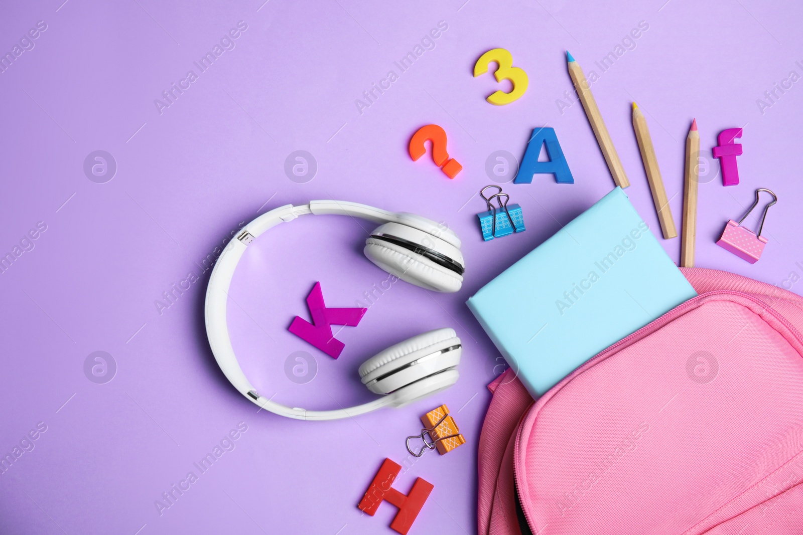 Photo of Flat lay composition with book and headphones on lilac background