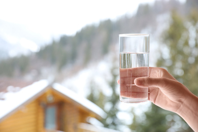 Photo of Woman holding glass of water outdoors on winter morning, closeup. Space for text