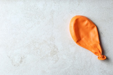 Photo of Orange deflated balloon on grey background, top view with space for text