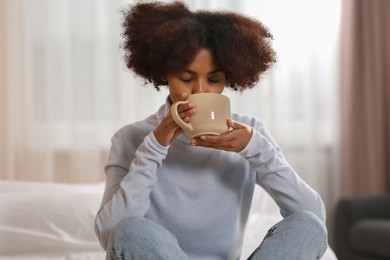 Photo of African American woman with cup of drink at home