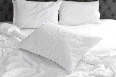 Comfortable bed with white linen and pillows at home