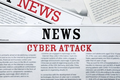 Photo of Newspapers with headline Cyber Attack as background, closeup