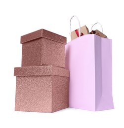 Photo of Pink paper shopping bag and gift boxes on white background