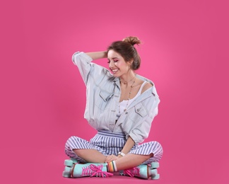 Young woman with retro roller skates on color background