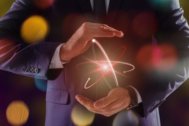 Image of Man holding virtual model of atom on color background, closeup
