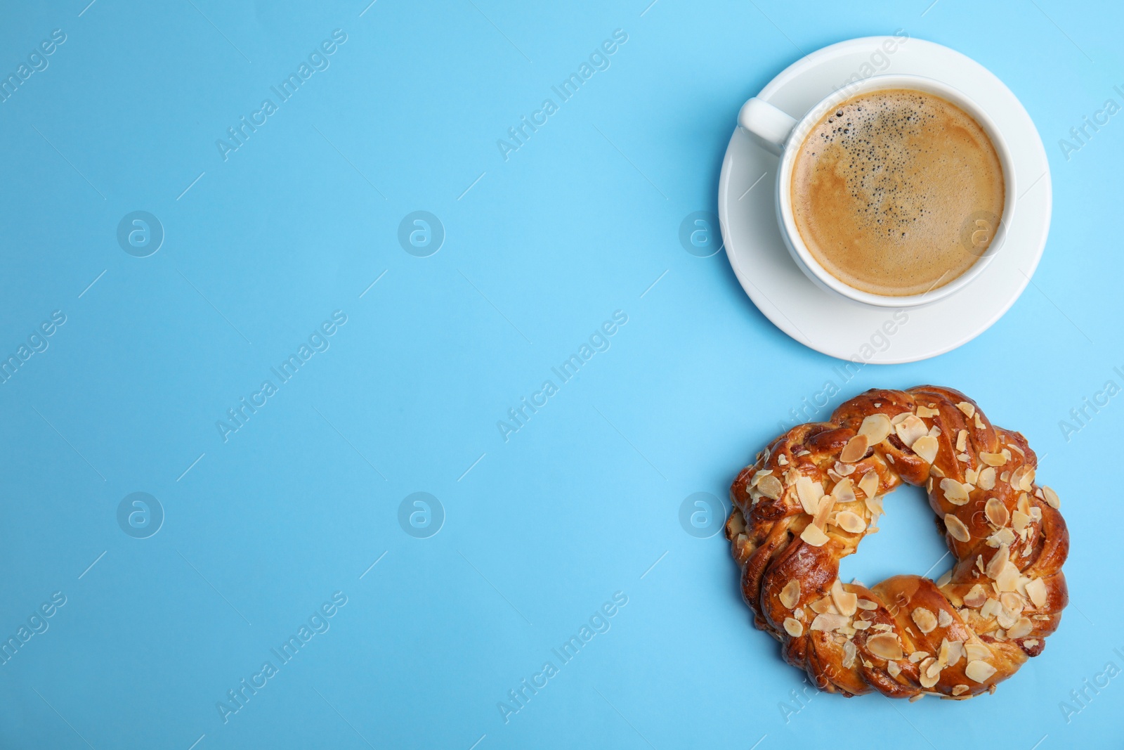 Photo of Delicious coffee and pastry on light blue background, top view. Space for text