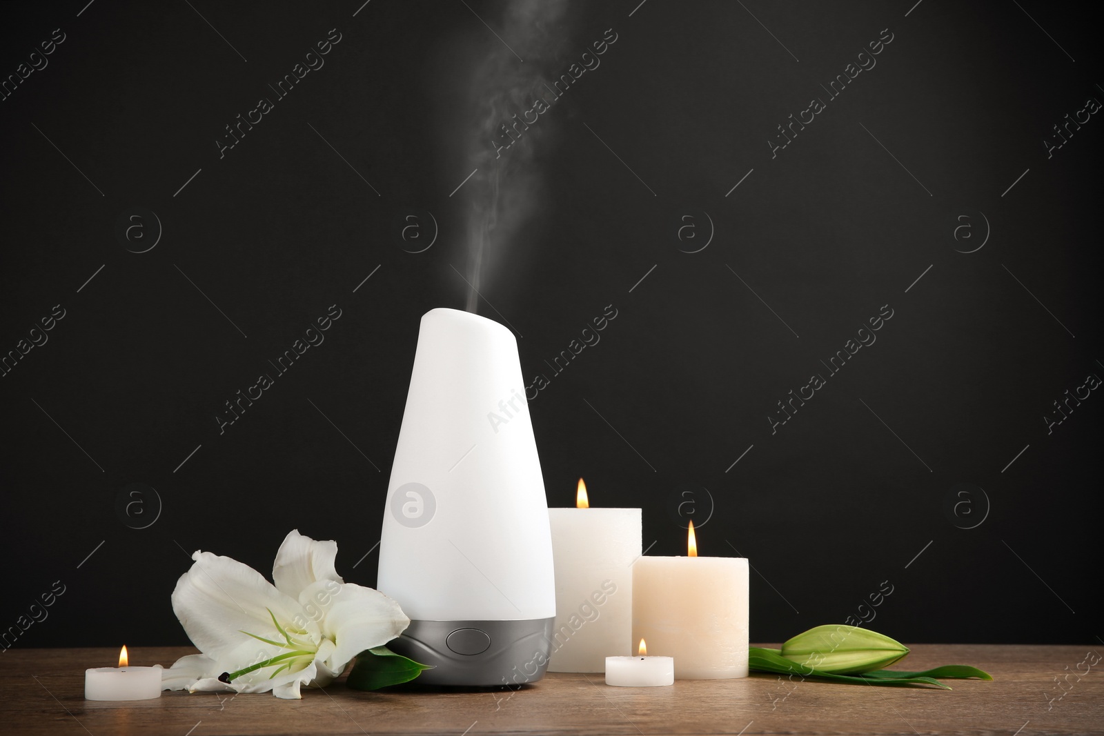 Photo of Composition with aroma humidifier on table against black background. Space for text