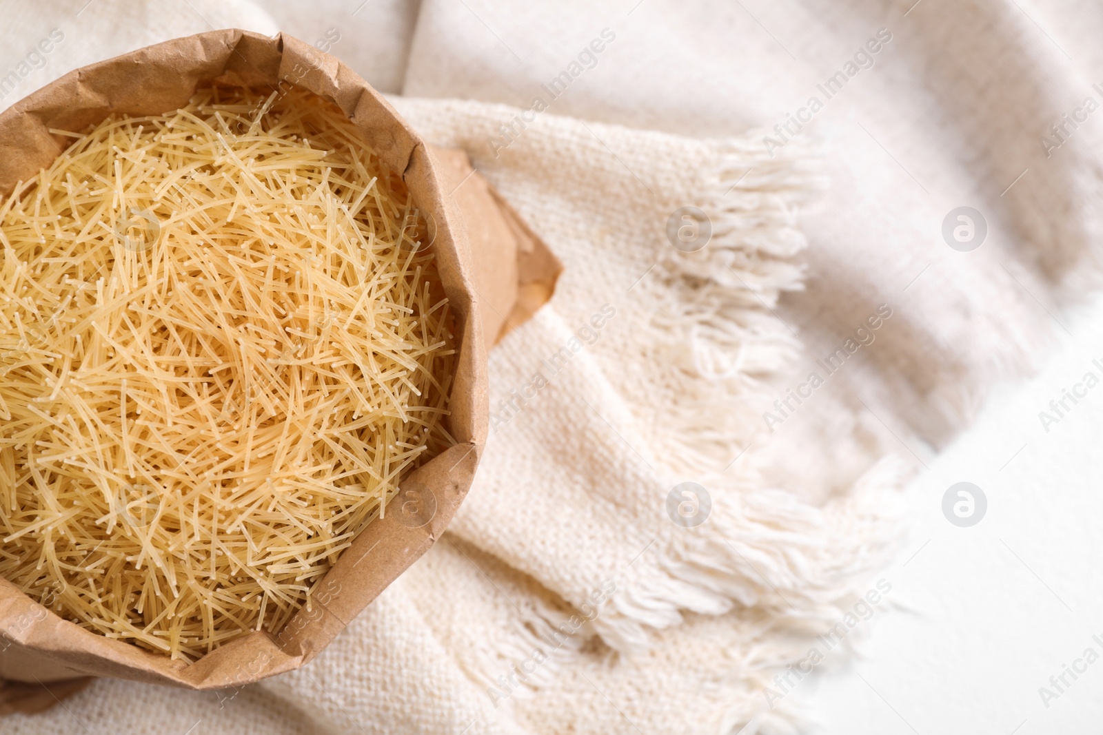 Photo of Uncooked filini pasta on white table, top view. Space for text