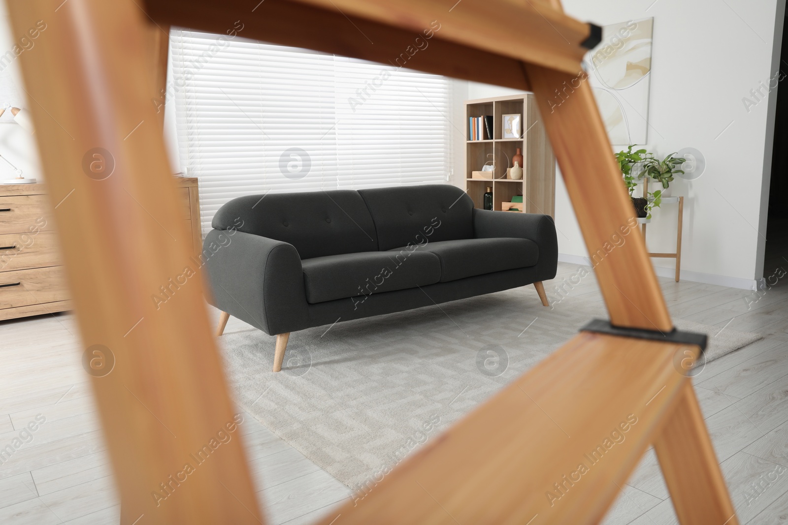 Photo of Comfortable sofa in living room, view through wooden ladder